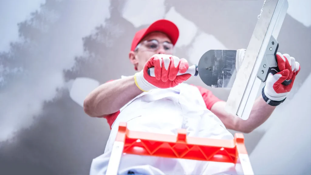 A man does a drywall on the ceiling of the house.