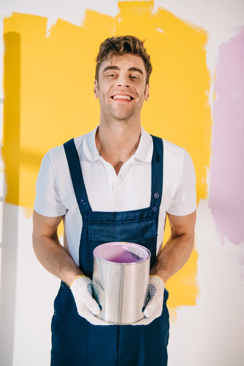 A cheerful young man holding a bucket of paint smiling.