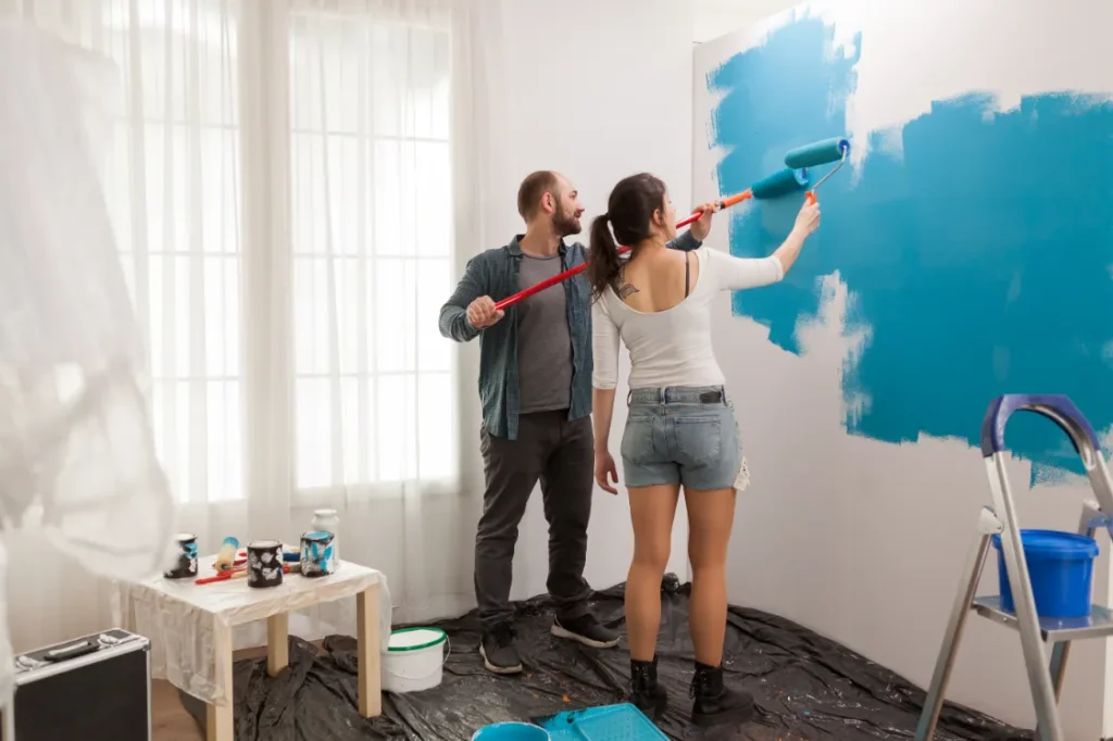 Couple painting the wall in the home.