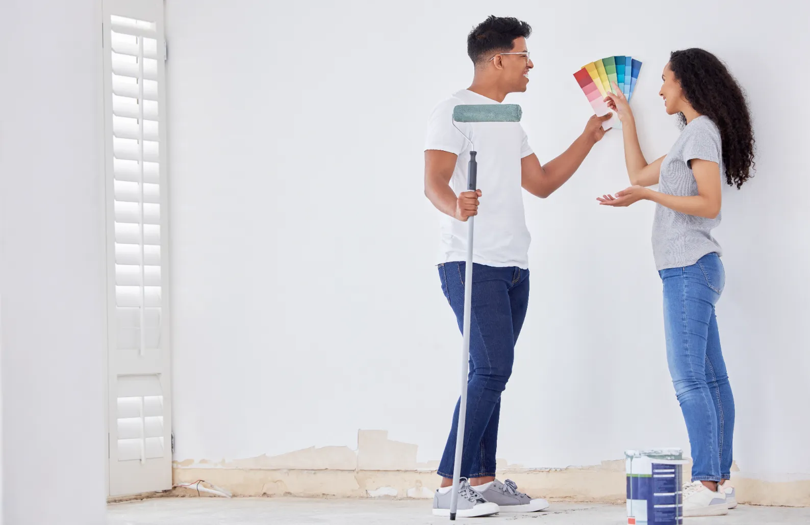 Couple placing the color swatches on the wall to decide the color to paint.