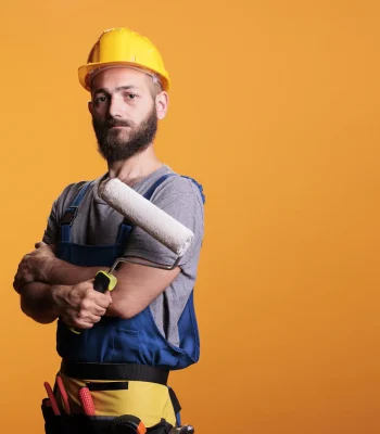 A worker posing while holding a paint roller.