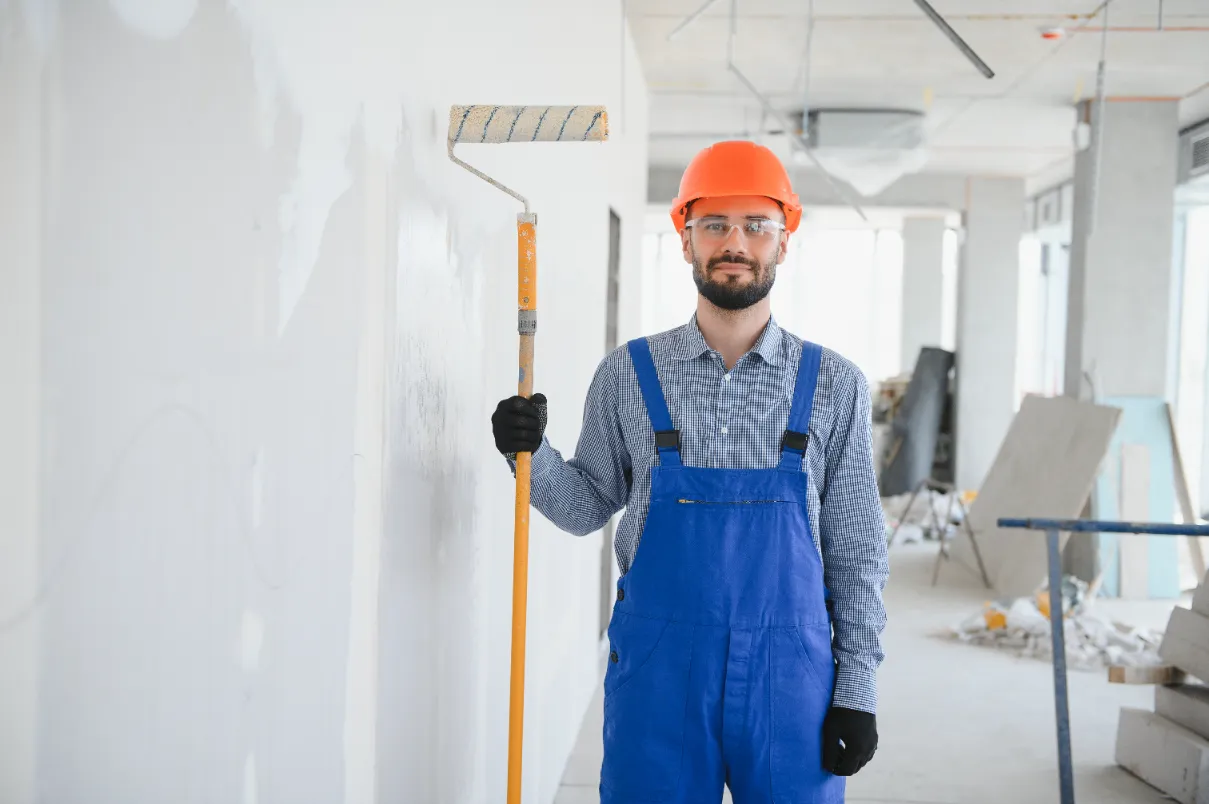 A man holding a long paint roller ready to work.