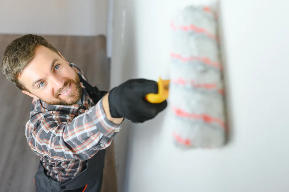 A man painting the wall with a paint roller.