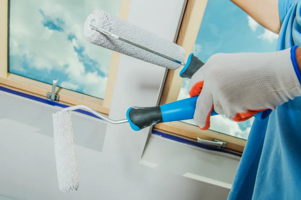 A zoomed images of a worker's hand holding paint rollers.